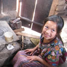 Girl cooking tortillas on wood stove in Guatemala.